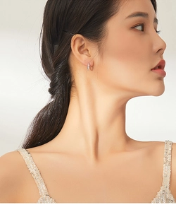 Close-up of minimalist S925 sterling silver hoop earring worn by a model in soft light