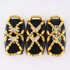 Detail of three black magic hair combs with gold beads, dragonfly and butterfly patterns