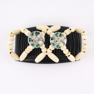 Detail of magic hair comb with beige wooden beads, tree of life metal décor and green rhinestones