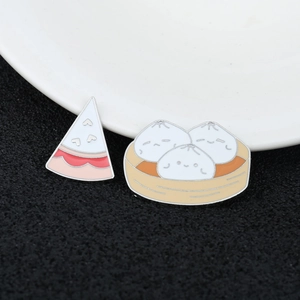 Detail of creative enamel pins featuring a slice of cake and baozi in a steamer basket