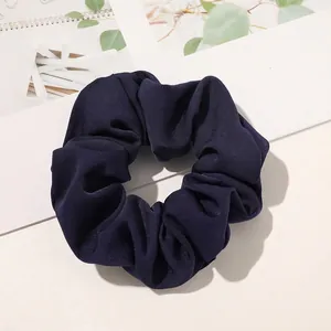 Detail of a dark blue pleated scrunchie showing the ribbed fabric texture and elastic design