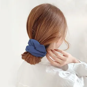 Detailed view of a navy blue striped fabric scrunchie styled on a low bun hairstyle