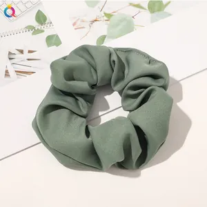 Close-up of olive green plaid fabric scrunchie showing detailed twill texture and soft sheen