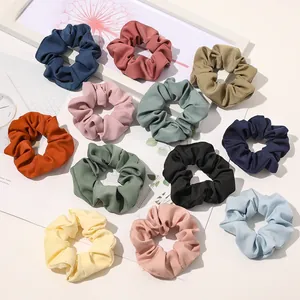 Detailed flat lay of 12 colorful fabric scrunchies in navy, pink, and mustard yellow