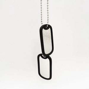 Close-up of dual stainless steel military dog tags with black silicone silencers on bead chain