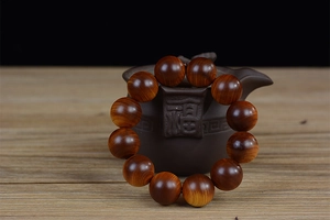Macro shot of 12 dark brown wooden beads with natural grain on a ceramic teapot