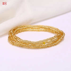 Close-up of bohemian layered golden seed bead waist chain on smooth white silk fabric