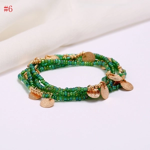 Detail of multi-layer green beads chain with gold frosted round pendants for beach wear