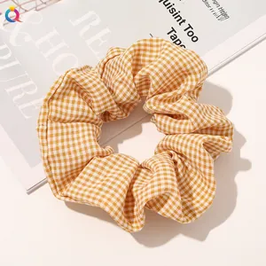 Macro detail of yellow gingham fabric hair scrunchie on a magazine background