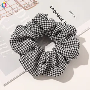 Detailed view of a black and white checkered fabric scrunchie with soft pleated texture