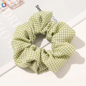 Detailed texture of a green and white gingham fabric scrunchie on a stylish book