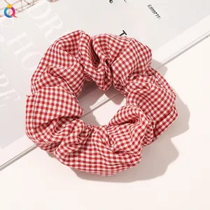 Close-up of a red and white gingham fabric scrunchie with detailed stitching on white magazine
