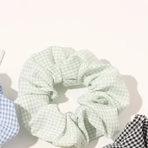 Plaid fabric scrunchies in mint green, light blue and black on a white background