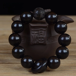 Vue détaillée d'un bracelet bouddhiste en bois noir de 20 mm sur une théière en céramique