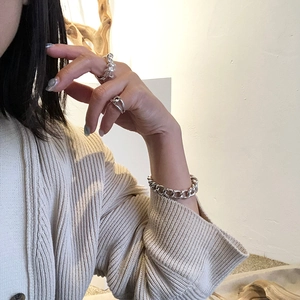 Detailed view of 925 silver twist ring and chunky chain bracelet on knitted sleeve