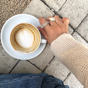Minimalist 925 sterling silver layered rings shown on a hand holding a coffee cup