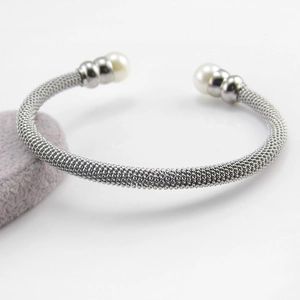 Detail eines silbernen Mesh-Manschettenarmbands mit Perlen auf grauem Samtständer