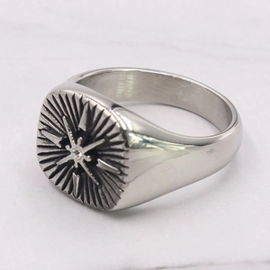 Close-up of square punk ring with starburst pattern and small gemstone inlay