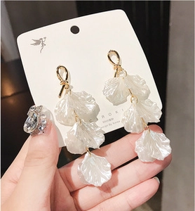Close-up of S925 silver needle earrings with iridescent translucent white petals