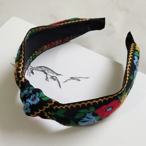 Close-up of bohemian knot headband featuring colorful ethnic floral embroidery details