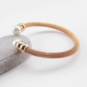Detail of rose gold mesh bracelet featuring dual pearls on a grey plush cushion