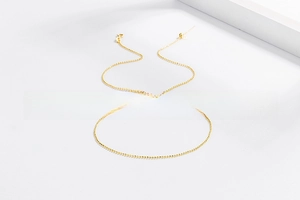 Close-up of a minimalist golden beaded chain with lobster clasp and adjustable tail