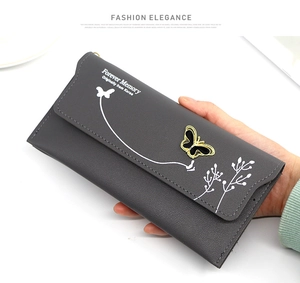 Close-up of gray long wallet featuring gold butterfly ornament and floral print textures