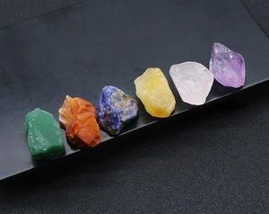 Macro shot of seven colorful raw natural healing crystal stones on dark background