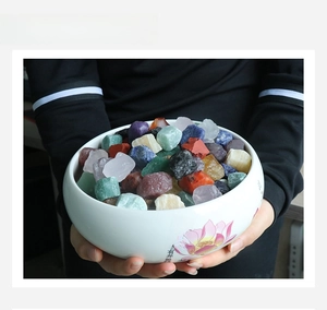 Hand holding a white ceramic bowl filled with raw amethyst, agate, and lapis lazuli stones