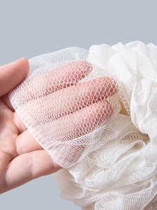 Close-up of white mesh bath sponge showing fine net texture and elastic material