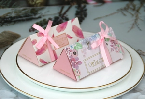 Dettaglio di scatola per caramelle triangolare rosa con motivi floreali e fiocco