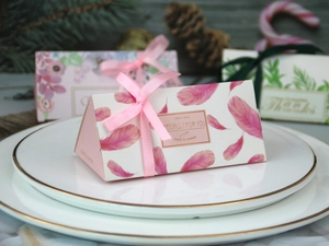 Dettaglio di scatole triangolari per confetti con nastri di seta e decorazioni floreali