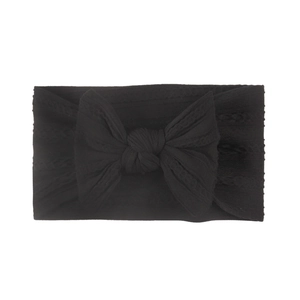 Detailed close-up of a black jacquard nylon baby headband with a large knit bow detail