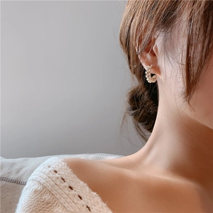 Close-up of elegant C-shaped hoop earrings featuring micro-set white pearls on a model