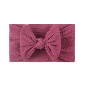 Close-up of soft jacquard nylon baby headband with large bow in dark pink color