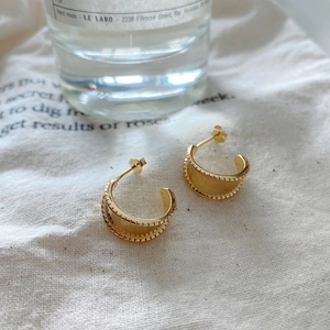 Macro detail of gold-plated S925 silver C-shape earrings with delicate milgrain edges