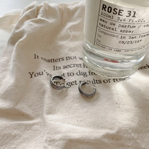 Close-up of vintage S925 silver twist hoop earrings with oxidized texture on canvas