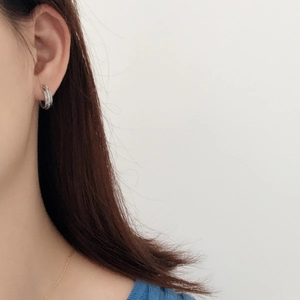 Close-up of woman wearing a small silver woven textured hoop earring in S925 sterling silver