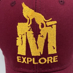 Gros plan d'une casquette bordeaux avec broderie détaillée d'un loup et de la lettre M