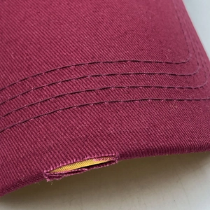Détail de la visière en coton sergé bordeaux avec coutures et bords effilochés