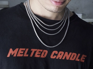 Close-up of layered silver tennis necklaces with sparkling crystals on a male model