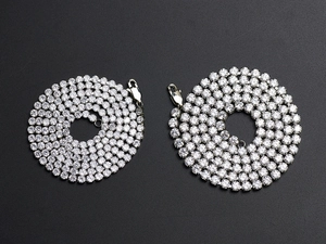 Top-down view of two layered silver hip-hop necklaces with sparkling zircon inlay