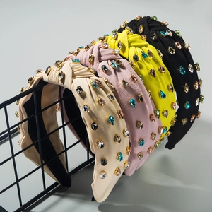 Detailed close-up of four assorted wide knotted headbands with sparkling rhinestones