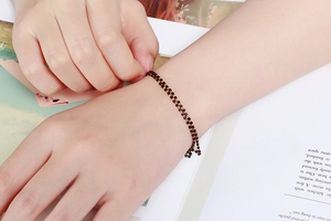 Gros plan d'un bracelet double couche en perles noires avec détails dorés sur un poignet