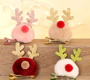 Detail view of four sequin reindeer antler hair clips with pom-poms on wooden surface