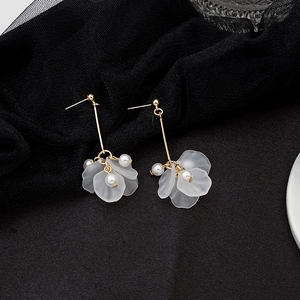 Detailed view of long petal pearl earrings with gold finish on black mesh fabric