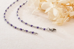 Detailed close-up of a stainless steel necklace with purple beads and lobster clasp