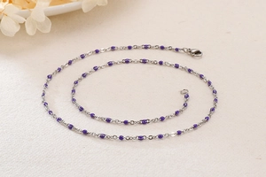 Detail of silver titanium steel chain featuring vibrant purple resin beads and lobster clasp