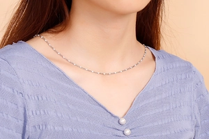 Detail of silver beaded chain necklace on model collarbone with delicate texture