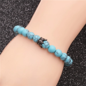 8mm blue turquoise bead bracelet with a black crown charm on a hand model
